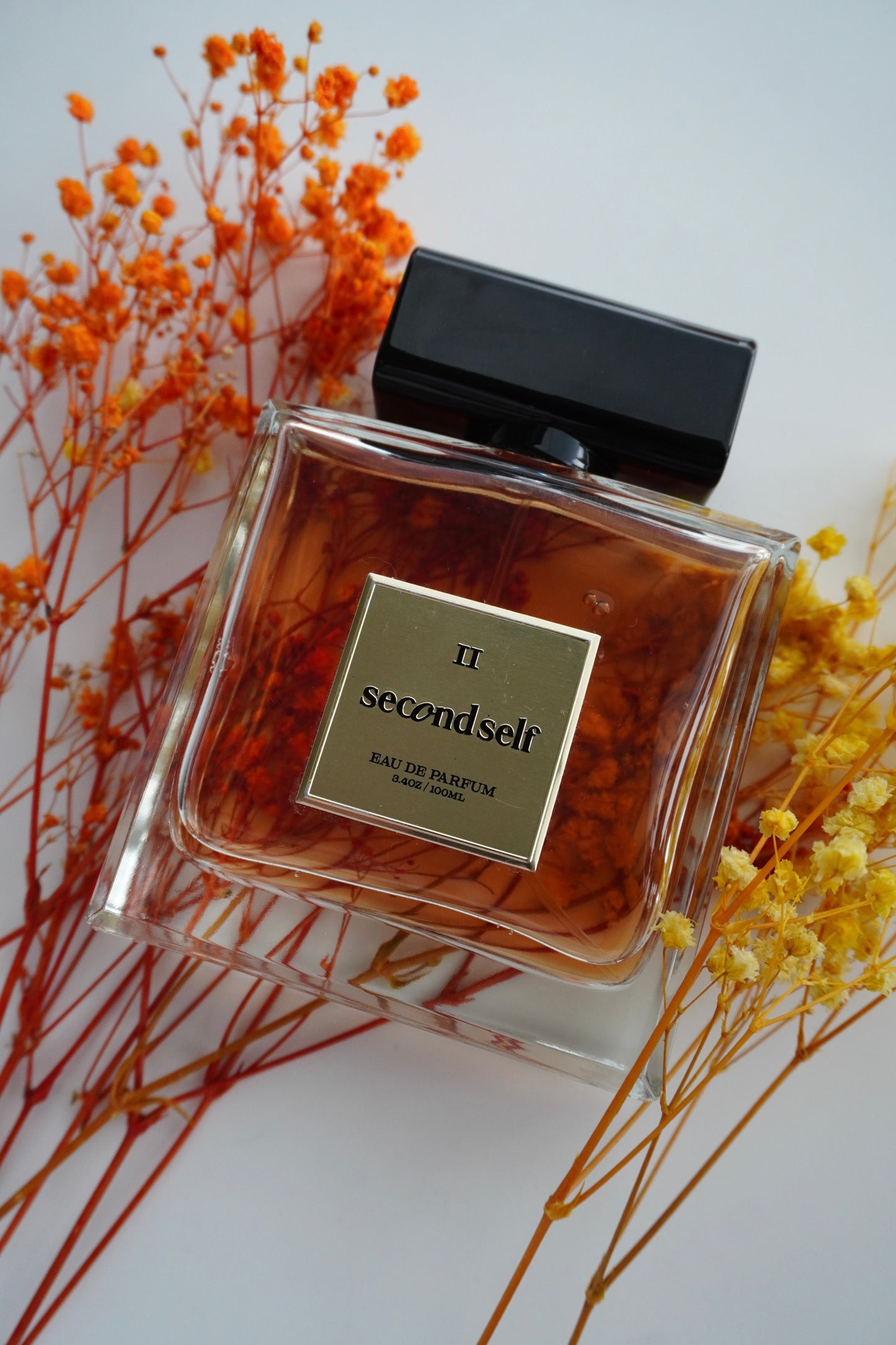 Second Self fragrance styled alongside a bouquet of fresh flowers.