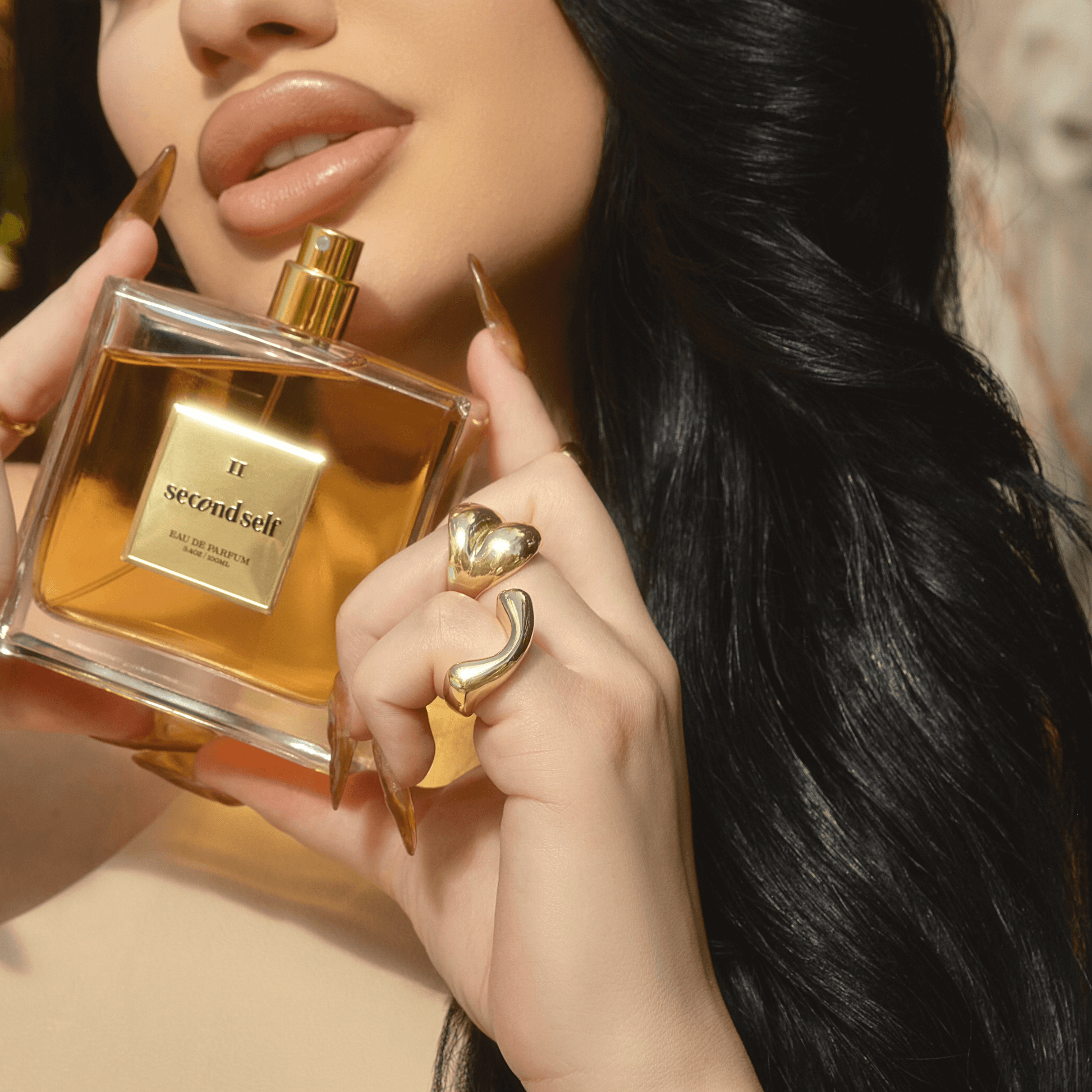 Briana Murillo posing with the Second Self fragrance holding it close to her face and showcasing the bottle.