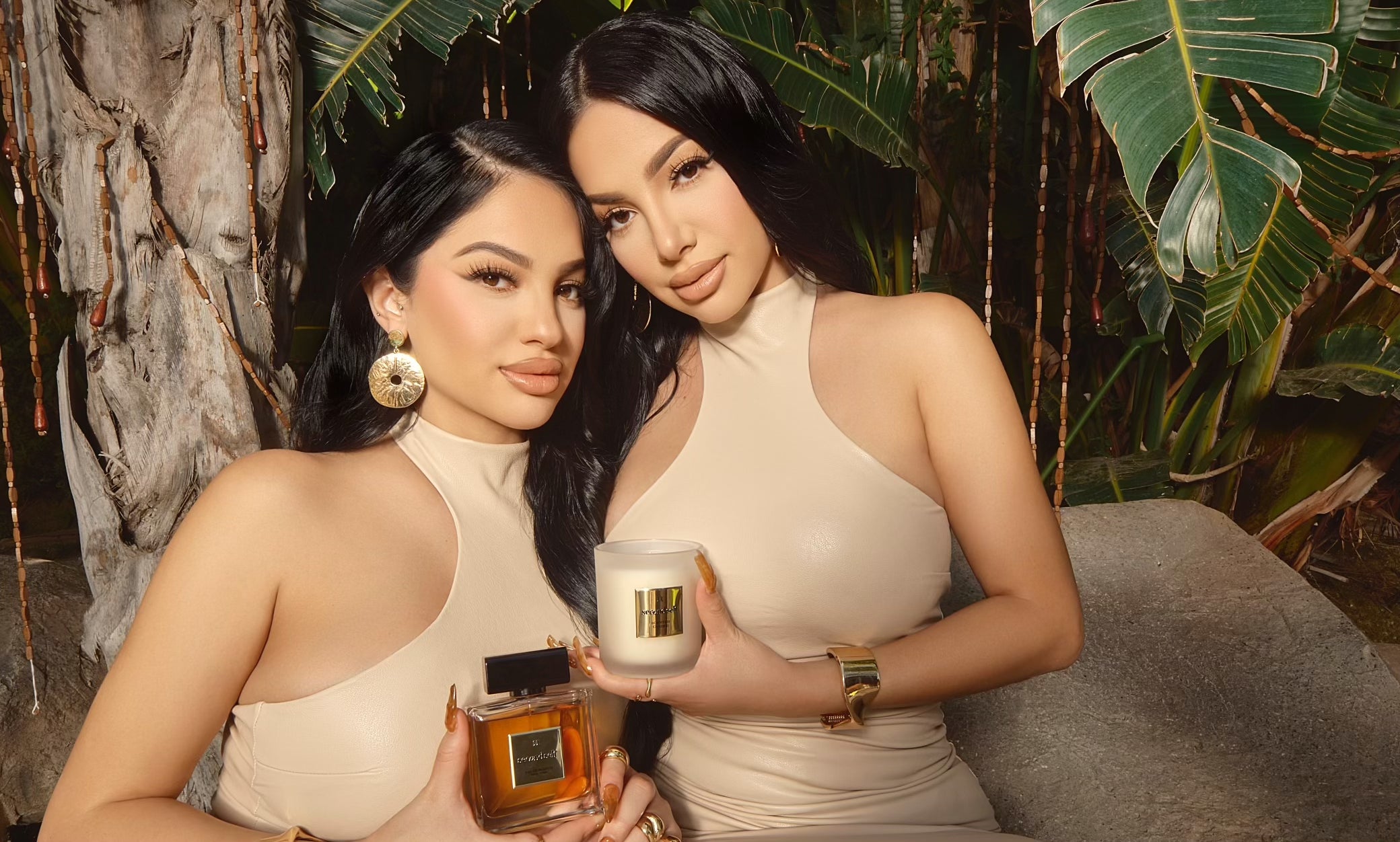 Brittany Murillo holding the Second Self fragrance and Briana Murillo holding the Second Self candle, sitting together in a forest setting.