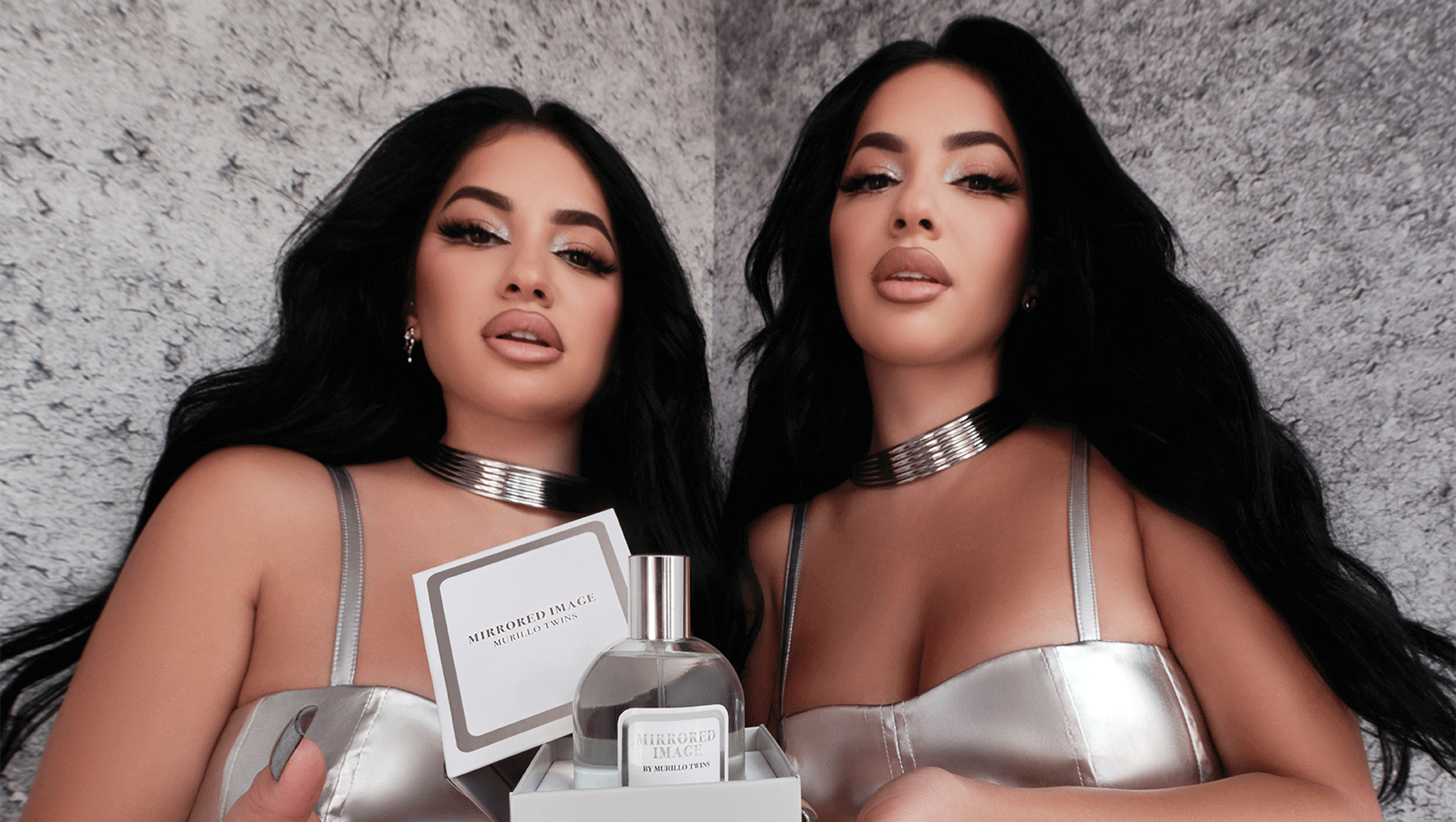 Brittany and Briana Murillo holding the box of the Mirrored Image fragrance, with the top set aside, showcasing the fragrance nestled inside the box.