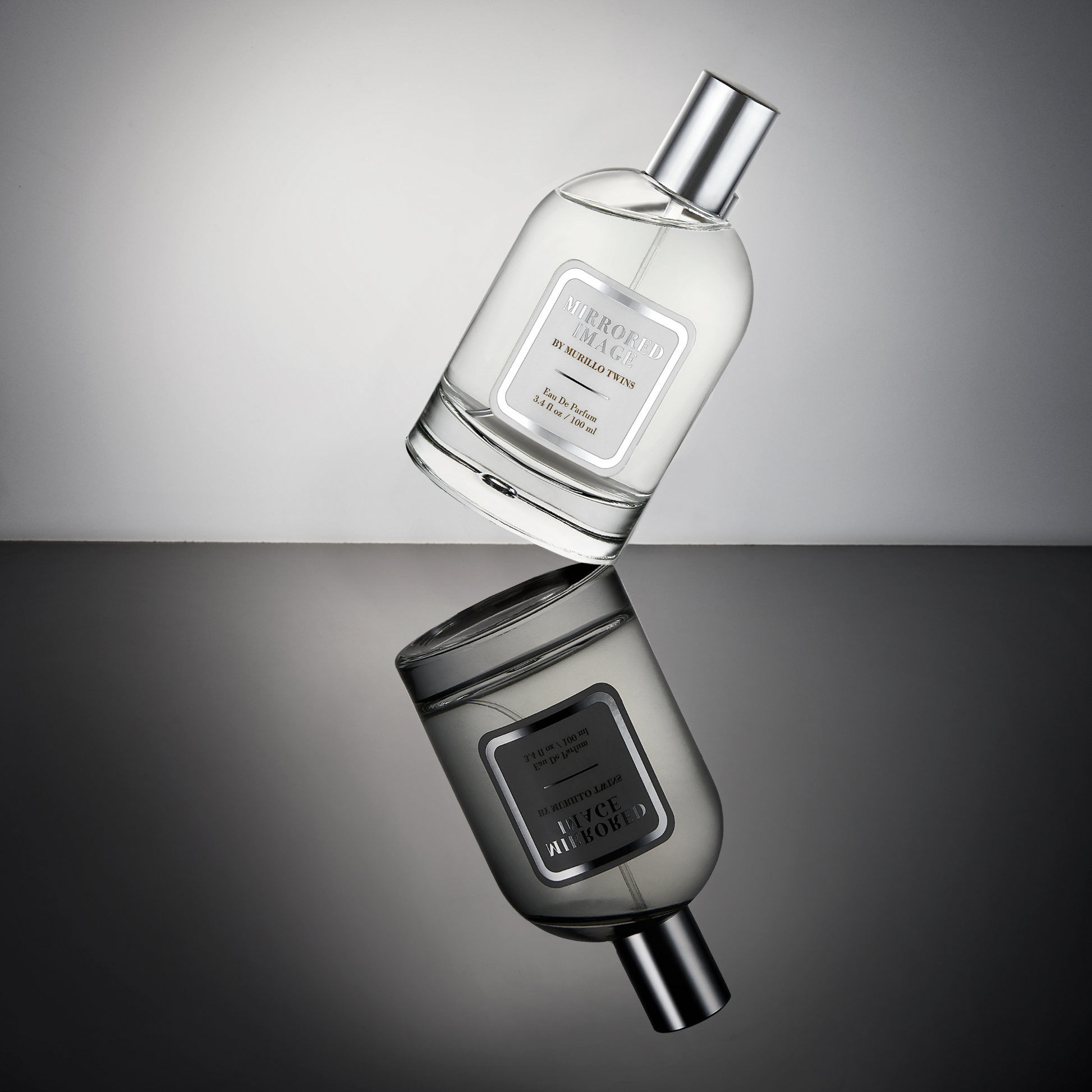 The Mirrored Image fragrance by The Murillo Twins displayed in a captivating product image, tilted on its side, showcasing elegance and uniqueness in its design.