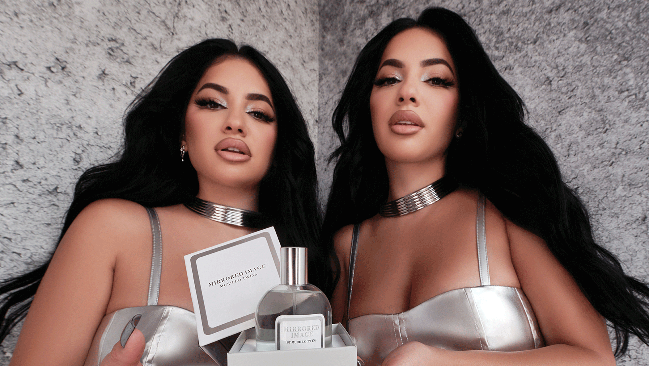 Image of the Murillo twin sisters elegantly posing with their signature fragrance 'Mirrored Image,' exuding confidence and sophistication.